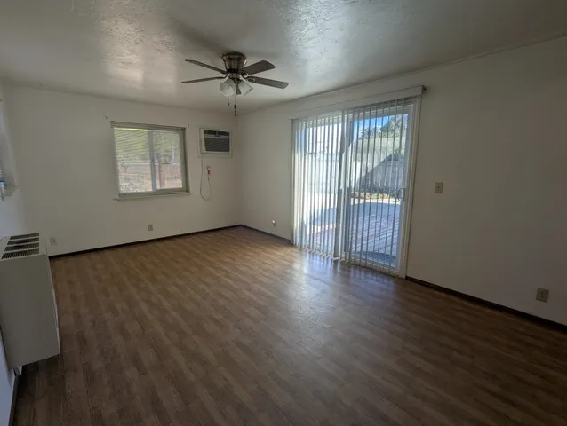 a view of an empty room with a window and wooden floor