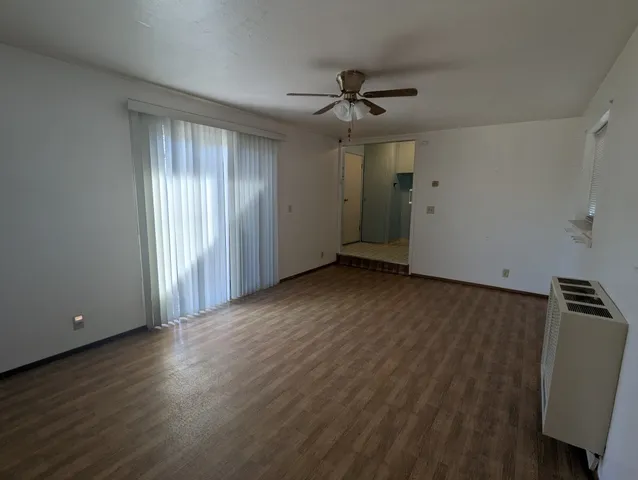 an empty room with wooden floor closet and windows