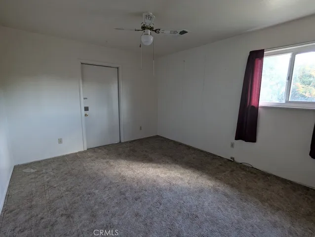 an empty room with windows and fan