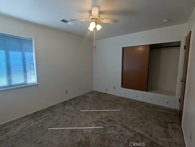 an empty room with a ceiling fan and a window