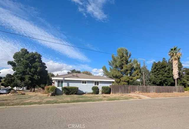 a front view of a house with a yard and trees in the background