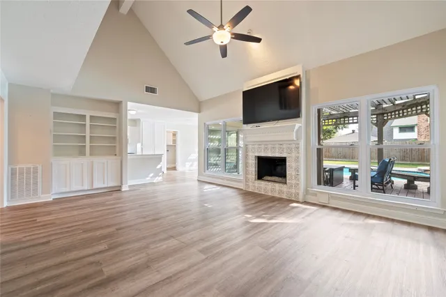 a view of a livingroom with a fireplace a ceiling fan and wooden floor