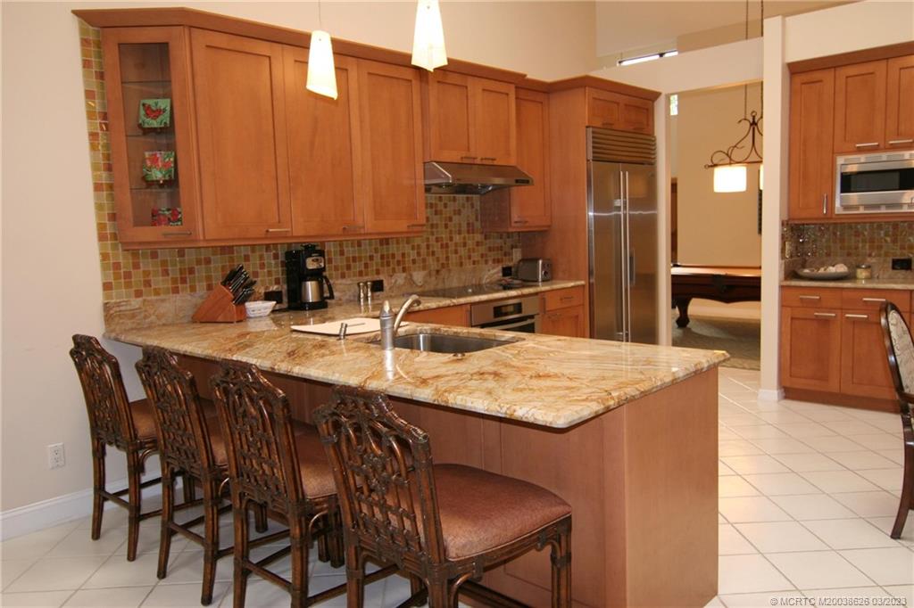 6945 Southeast Harbor Circle Stuart, FL 34996 - Photo 2 of 11 a kitchen with stainless steel appliances granite countertop a sink table and chairs
