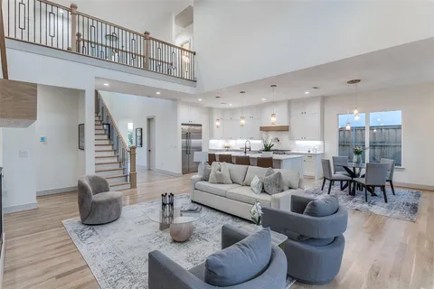 a living room with furniture kitchen view and a wooden floor