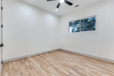 an empty room with a ceiling fan and wooden floor