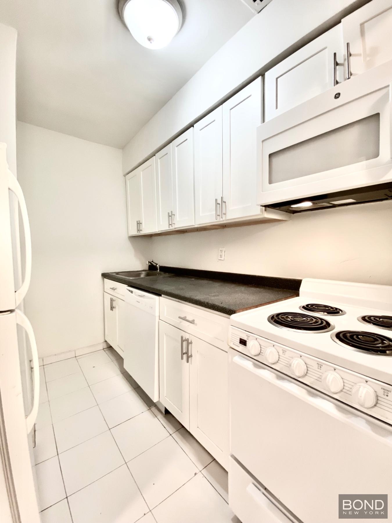 345 East 72nd Street, Unit 2A Manhattan, NY 10021 - Photo 4 of 10 a kitchen with granite countertop white cabinets and white appliances