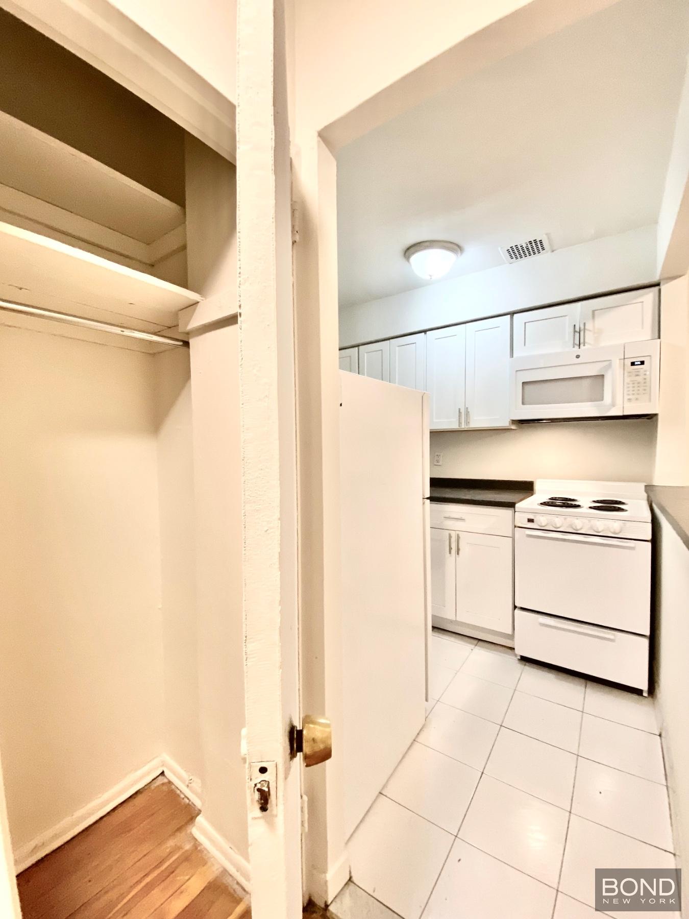 345 East 72nd Street, Unit 2A Manhattan, NY 10021 - Photo 6 of 10 a kitchen with a refrigerator and white cabinets