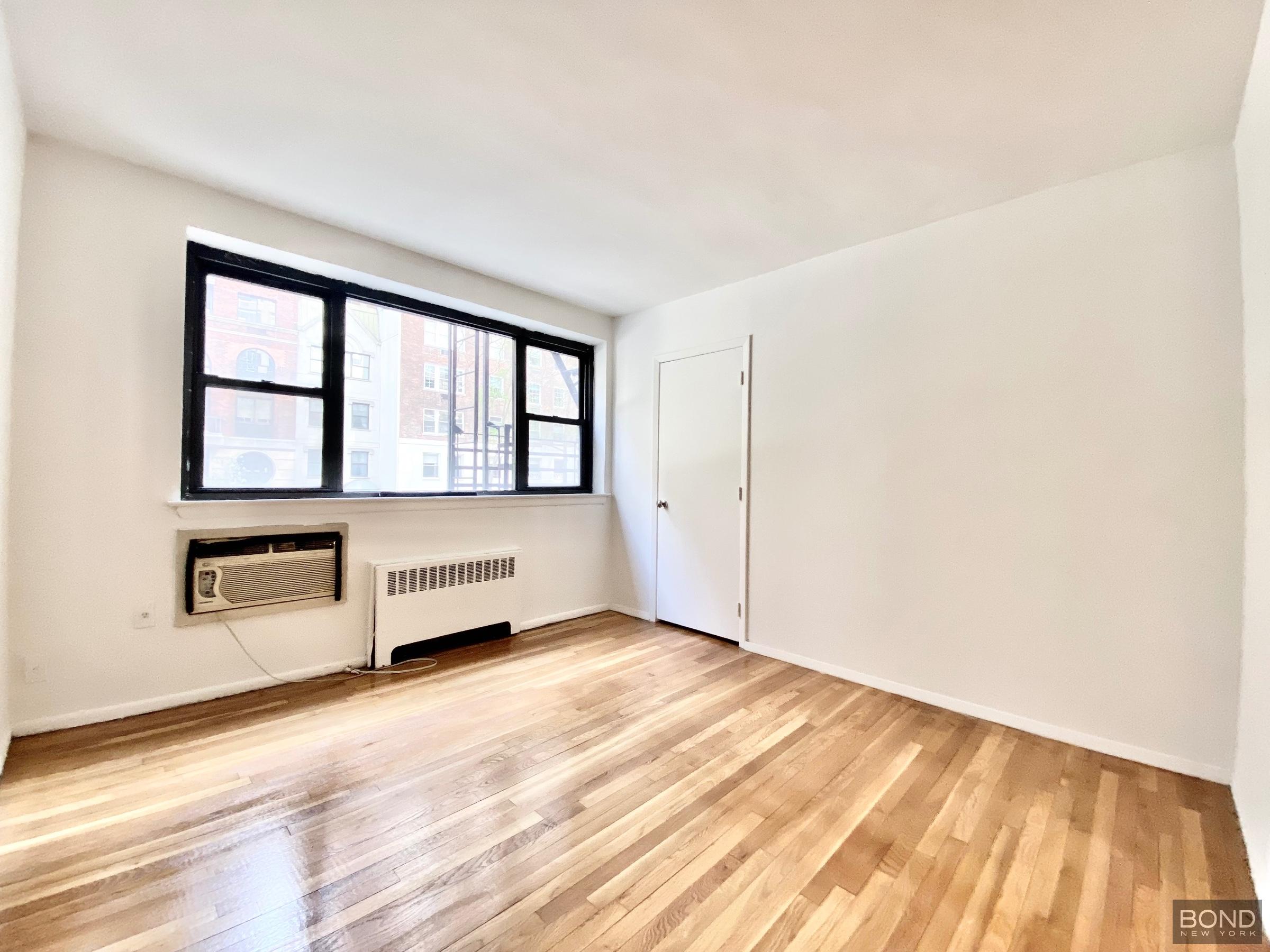 345 East 72nd Street, Unit 2A Manhattan, NY 10021 - Photo 8 of 10 an empty room with wooden floor and windows