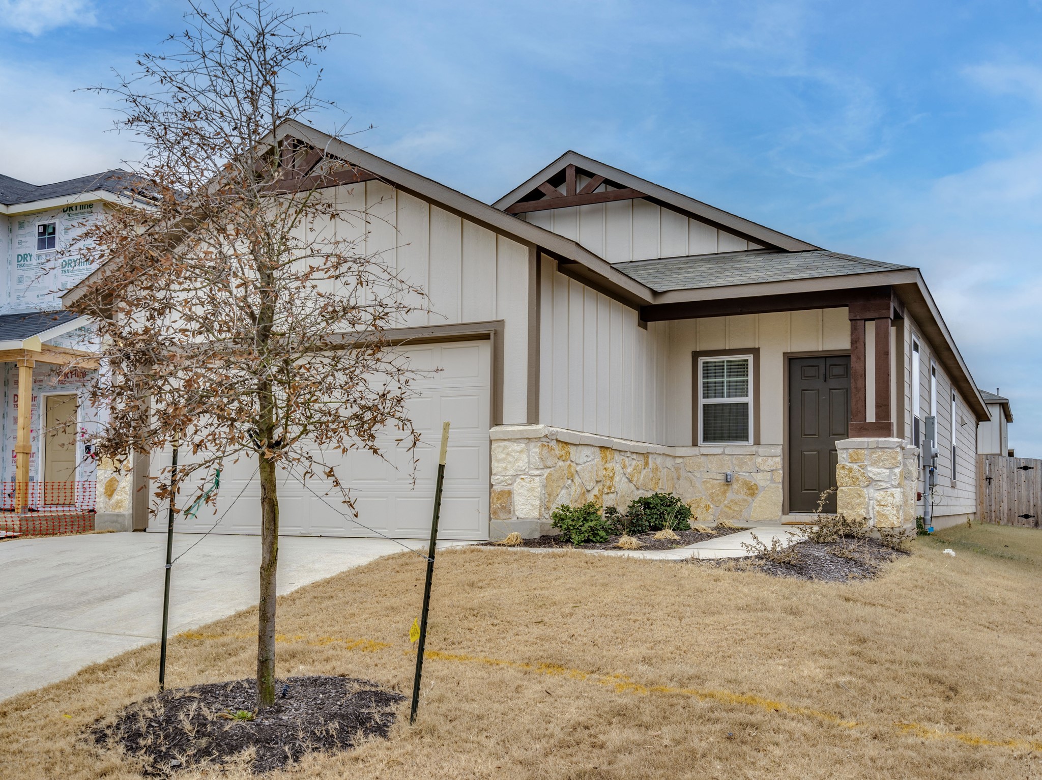 388 Begonia Street Buda, TX 78610 - Photo 2 of 21 View of front of house featuring board and batten siding, driveway, an attached garage, and stone siding