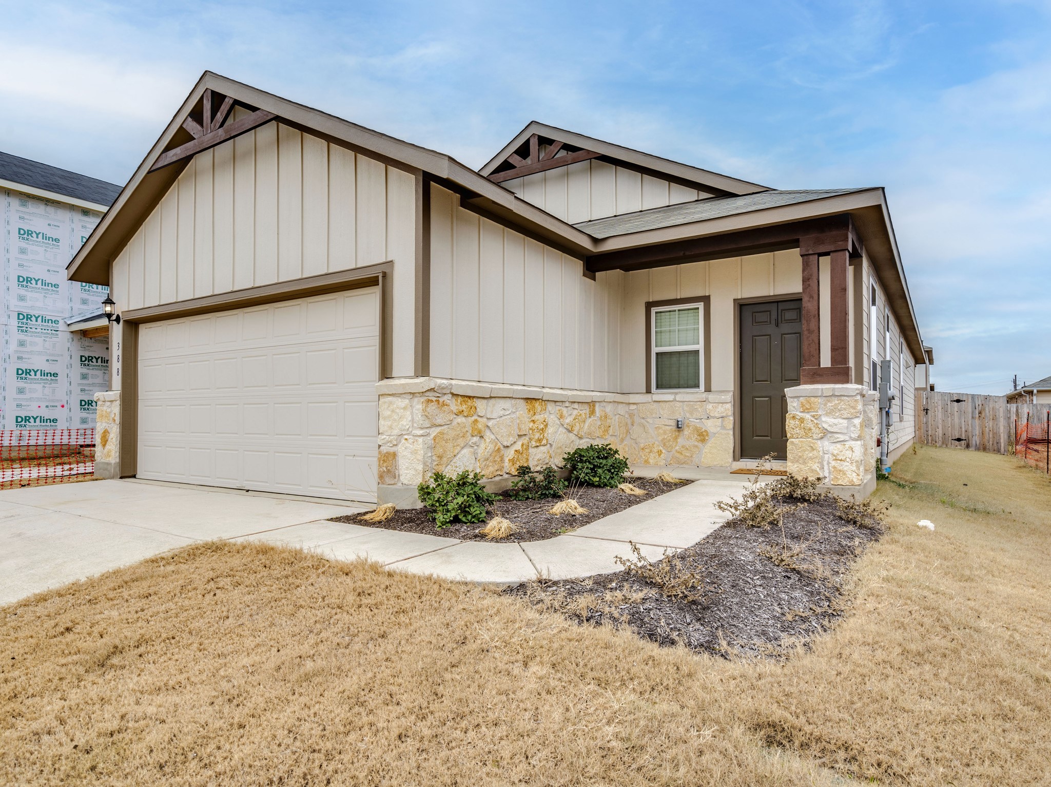 388 Begonia Street Buda, TX 78610 - Photo 3 of 21 View of front of property featuring board and batten siding, driveway, a garage, and stone siding
