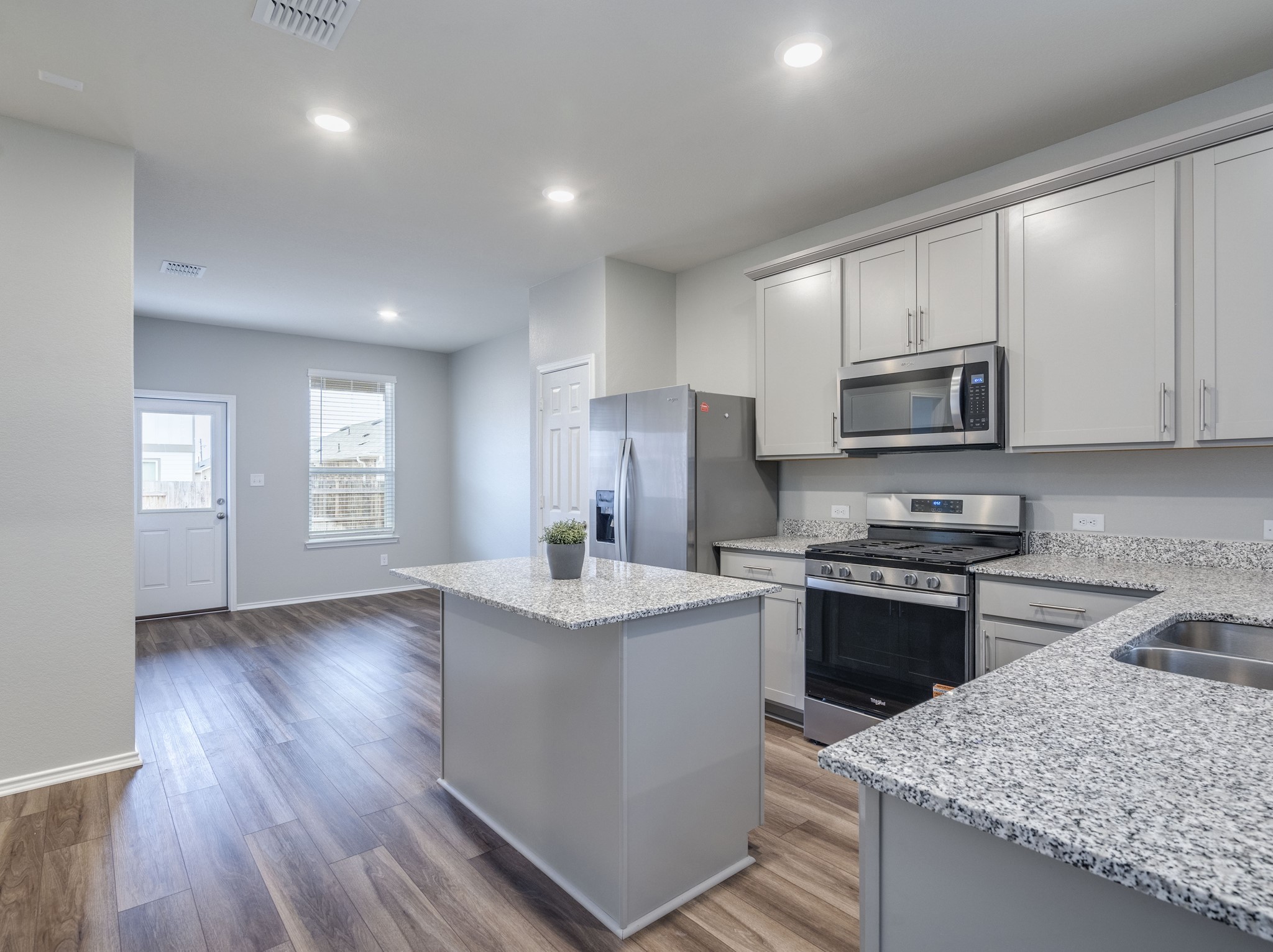 388 Begonia Street Buda, TX 78610 - Photo 7 of 21 Kitchen featuring stainless steel appliances, a center island, light stone counters, dark wood-type flooring, and recessed lighting
