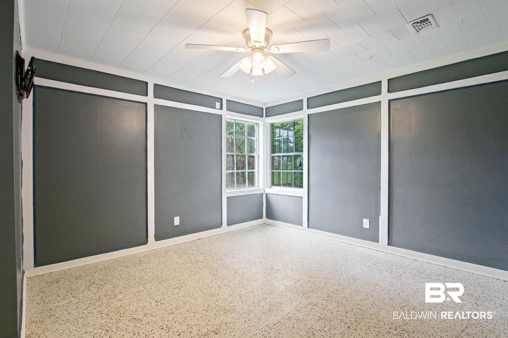 384 Old Bratt Road Atmore, AL 36502 - Photo 45 of 64 Corner window feature with multiple panes, ceiling fan light fixture, tray ceiling with white paneling, board and batten wall details, and speckled flooring
