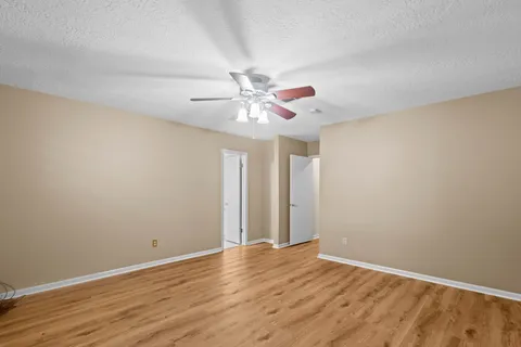an empty room with wooden floor and ceiling fan