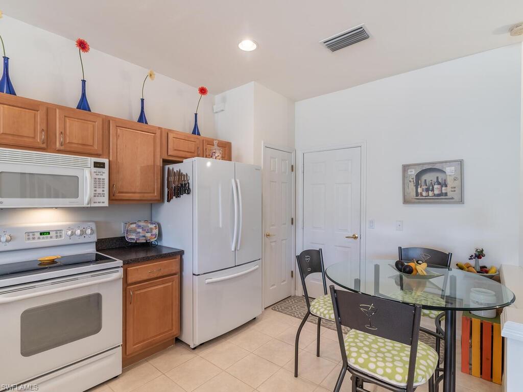 953 Hampton Circle, Unit 112 Naples, FL 34105 - Photo 5 of 35 a kitchen with stainless steel appliances a stove a sink refrigerator and white cabinets with wooden floor