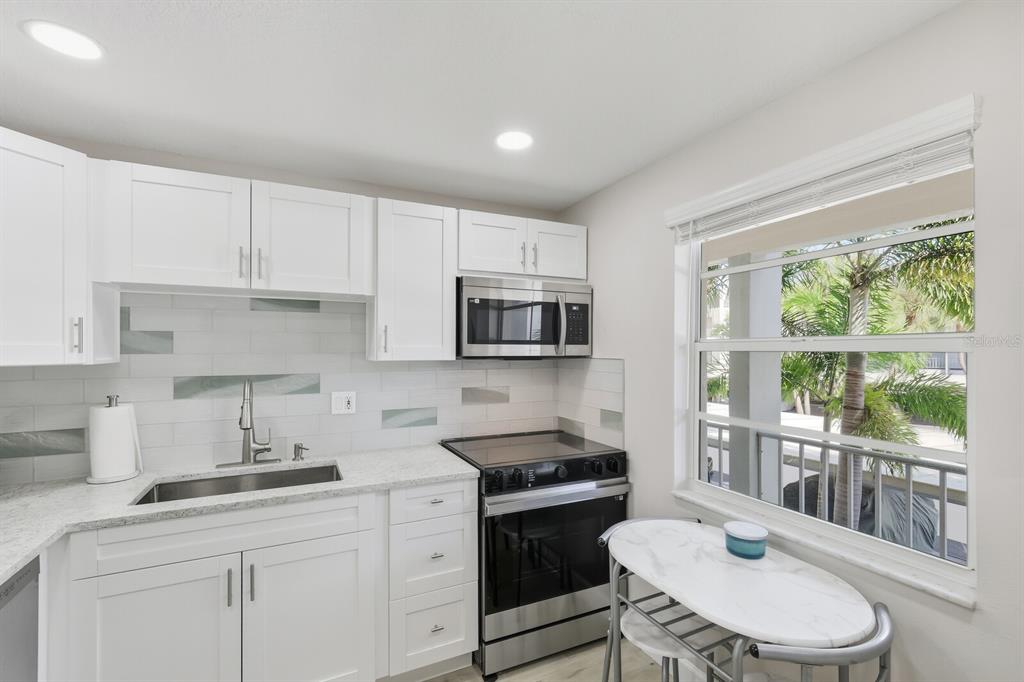 4380 Exeter Drive, Unit H202 Longboat Key, FL 34228 - Photo 12 of 37 a kitchen with stainless steel appliances a sink a stove a refrigerator cabinets and a window