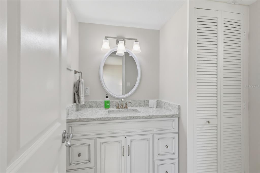4380 Exeter Drive, Unit H202 Longboat Key, FL 34228 - Photo 20 of 37 a bathroom with a granite countertop sink a mirror and a vanity