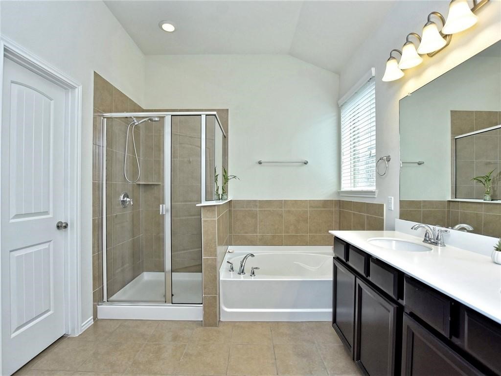 305 Methodius Drive Hutto, TX 78634 - Photo 14 of 26 a bathroom with a sink a mirror and a bathtub