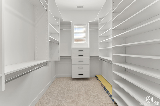 707 Spring Lily Drive St. George, UT 84790 - Photo 25 of 43 Walk-in closet with extensive built-in shelving, multiple hanging rods, a central drawer unit, and a window for natural light