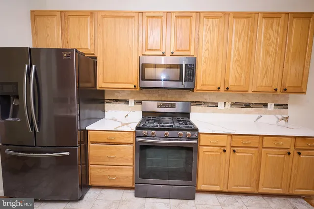 a kitchen with stainless steel appliances granite countertop a stove a refrigerator and a microwave