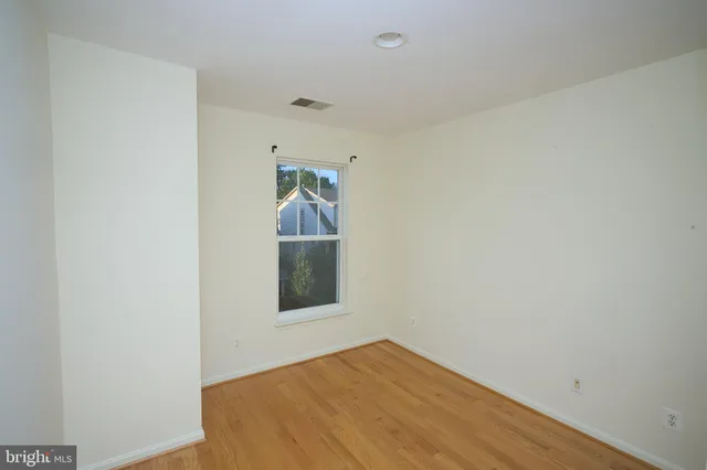 a view of empty room with window and wooden floor