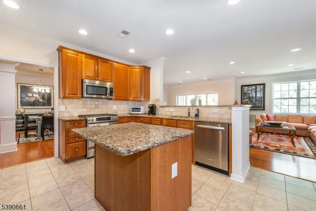 a kitchen with stainless steel appliances granite countertop a stove top oven a sink a counter top space cabinets and living room view