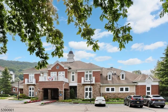 a front view of a building with lot of cars and trees