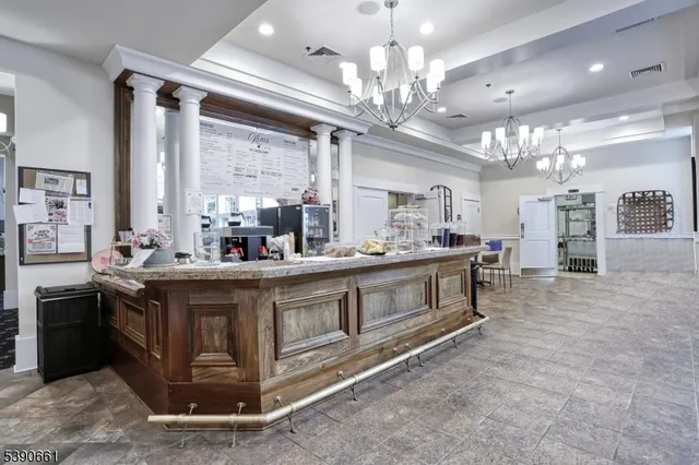 a view of living room kitchen with stainless steel appliances granite countertop furniture and a chandelier