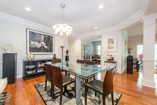 a dining room with wooden floor a chandelier a wooden table and chairs