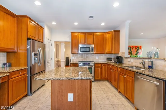 a kitchen with stainless steel appliances granite countertop sink stove refrigerator and cabinets