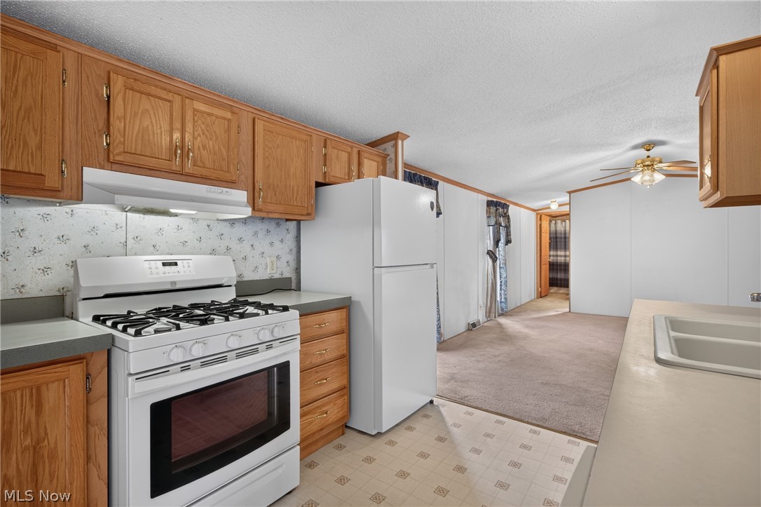 35157 Center Ridge Road, Unit 153 North Ridgeville, OH 44039 - Photo 18 of 35 Kitchen featuring wood cabinetry, white gas range with overhead ventilation, and a double basin sink