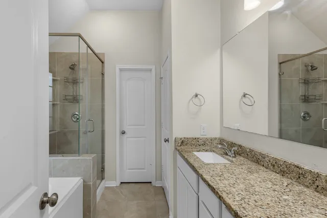 a bathroom with a granite countertop sink a shower and a mirror