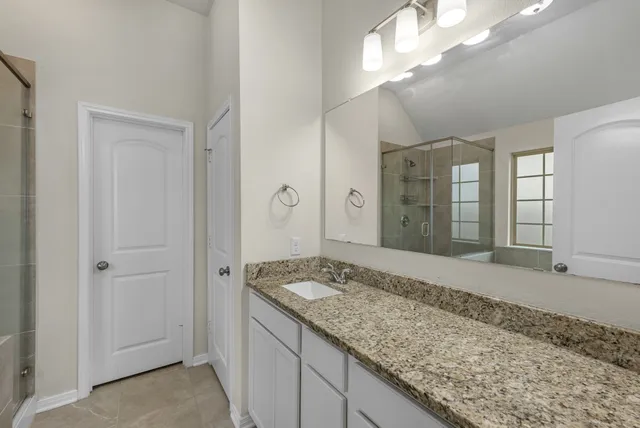 a bathroom with a granite countertop sink and a mirror