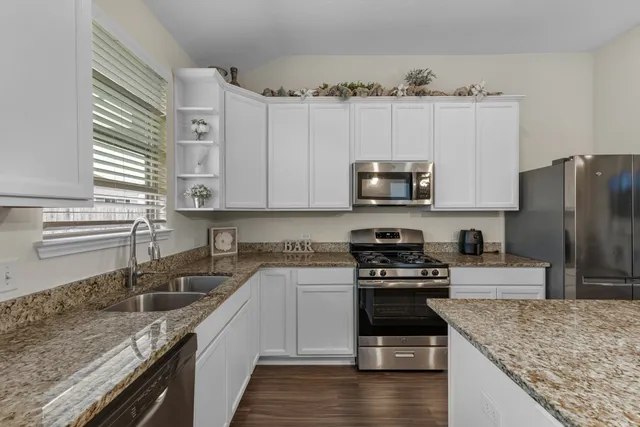 a kitchen with granite countertop a stove sink and refrigerator