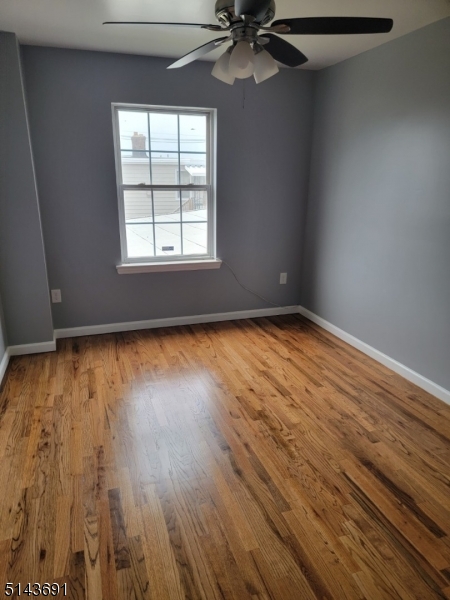 232 Amity Street, Unit 1 Elizabeth, NJ 07202 - Photo 3 of 11 an empty room with wooden floor fan and windows