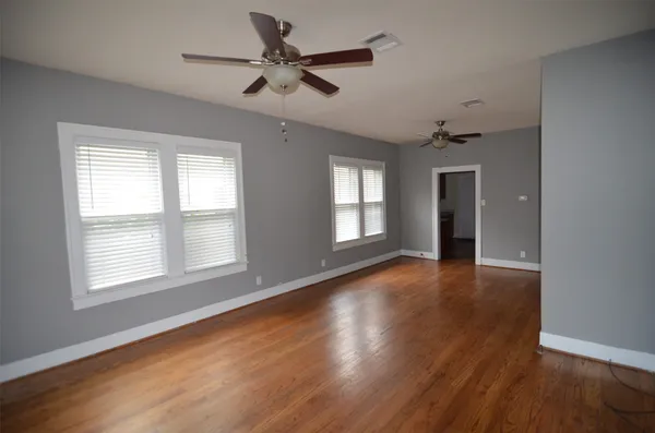 a view of an empty room with a window and wooden floor