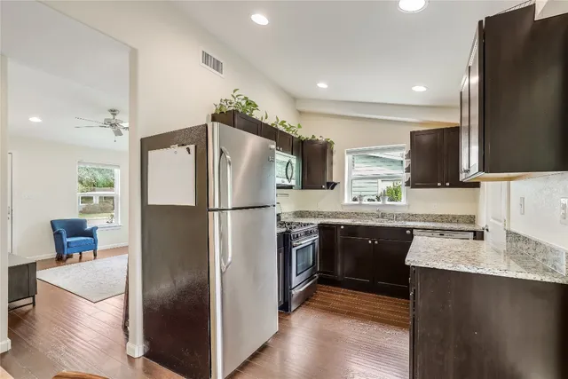 a kitchen with stainless steel appliances granite countertop a refrigerator a sink a stove a microwave and island