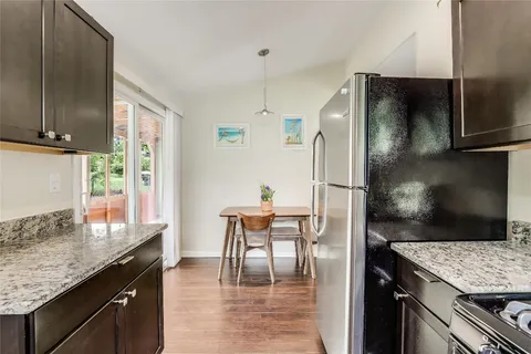 a kitchen with granite countertop a refrigerator a stove and a sink with wooden floor