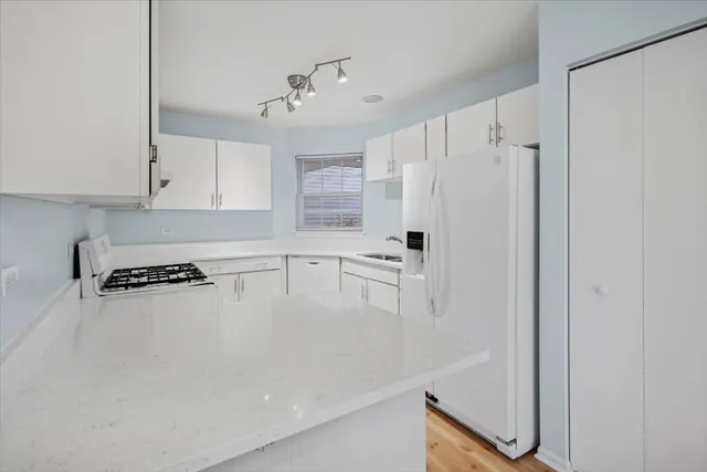 a kitchen with stainless steel appliances granite countertop a refrigerator a sink and white cabinets