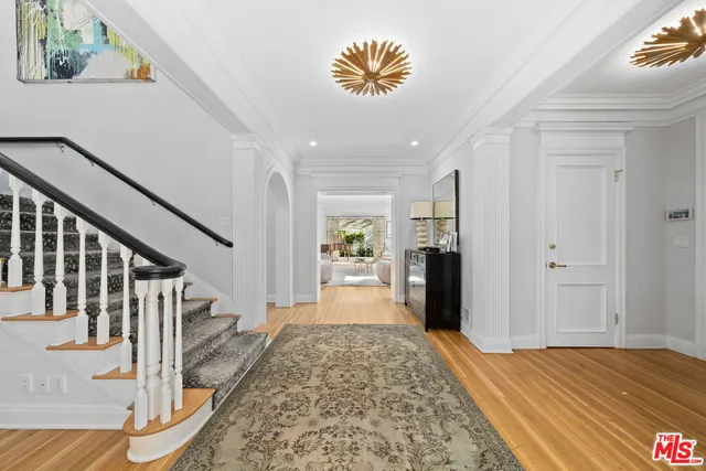 a view of a hallway to a livingroom with wooden floor and furniture