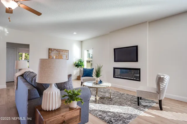 a living room with furniture kitchen view and a wooden floor