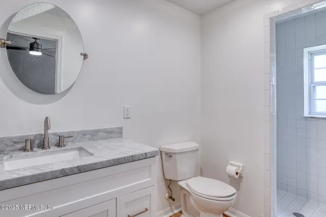 a bathroom with a granite countertop toilet a sink and mirror
