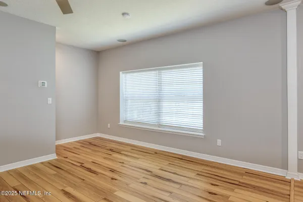 a view of an empty room with wooden floor and a window