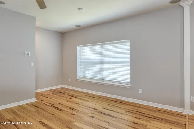 a view of an empty room with wooden floor and a window