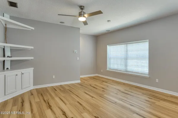 a view of an empty room with a window and a dresser