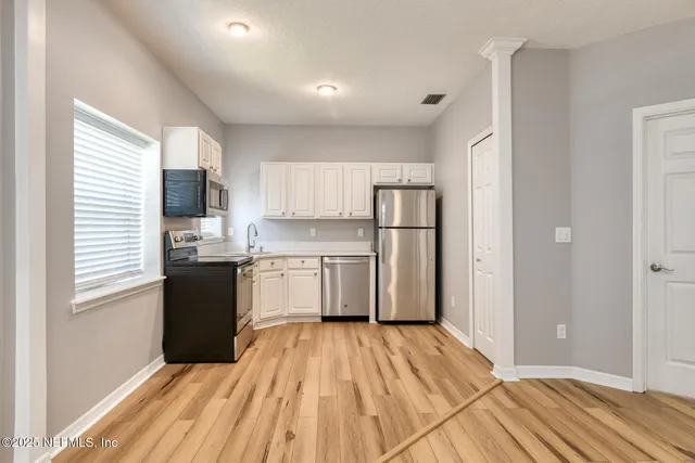 a kitchen with a refrigerator a stove top oven a sink and dishwasher with wooden floor