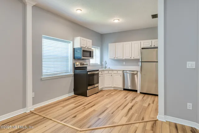 a kitchen with a refrigerator a stove top oven a sink dishwasher and wooden floor