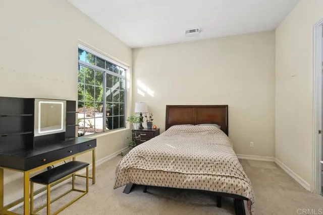 a bedroom with a bed and a flat tv screen next to a window