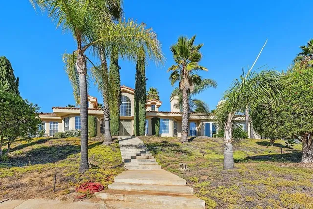 a view of a house with palm tree next to a yard