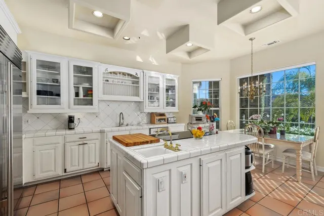 a kitchen that has a sink and chairs in it