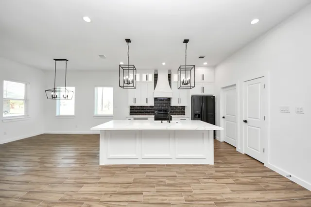 a large white kitchen with a large island oven a stove and a wooden floors